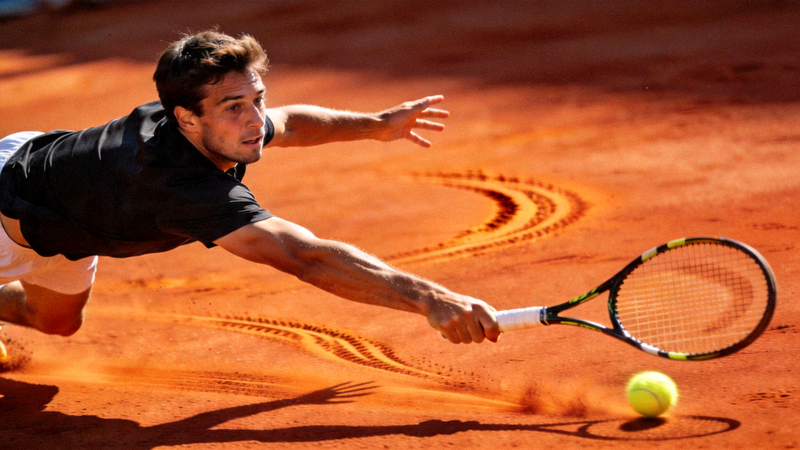 网球运动员在红土场上奋力救球的动作瞬间 - 表情专注